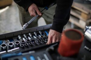 Mechanic selecting a socket wrench from a professional tool tray in an auto repair shop workshop