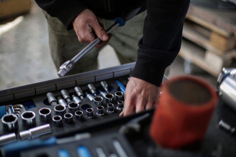 Mechanic selecting a socket wrench from a professional tool tray in an auto repair shop workshop